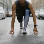 Determined woman in athletic pose ready to sprint on a wet city street.