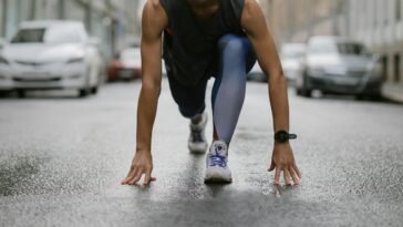 Determined woman in athletic pose ready to sprint on a wet city street.