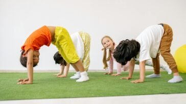 Happy children engaging in playful exercise and learning indoors, fostering group togetherness.