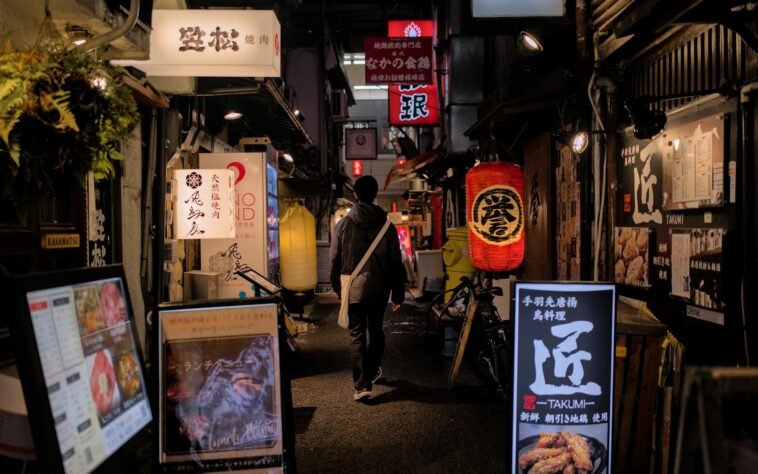 Explore Osaka's vibrant nightlife with a stroll through its illuminated alleys filled with signs and lanterns.