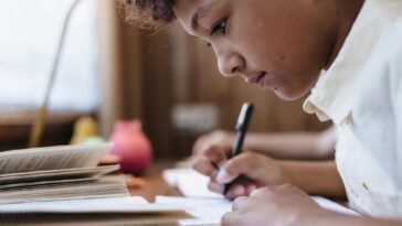 A young boy intensely writing indoors, capturing a moment of concentration.