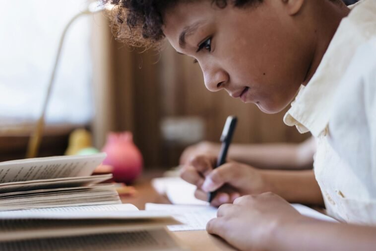 A young boy intensely writing indoors, capturing a moment of concentration.