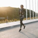 A woman jogging on a sunny outdoor path, showcasing fitness and sport.