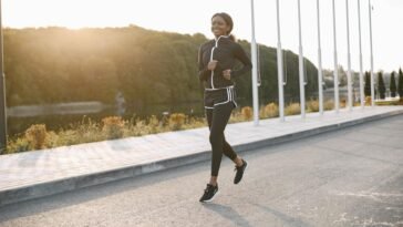 A woman jogging on a sunny outdoor path, showcasing fitness and sport.