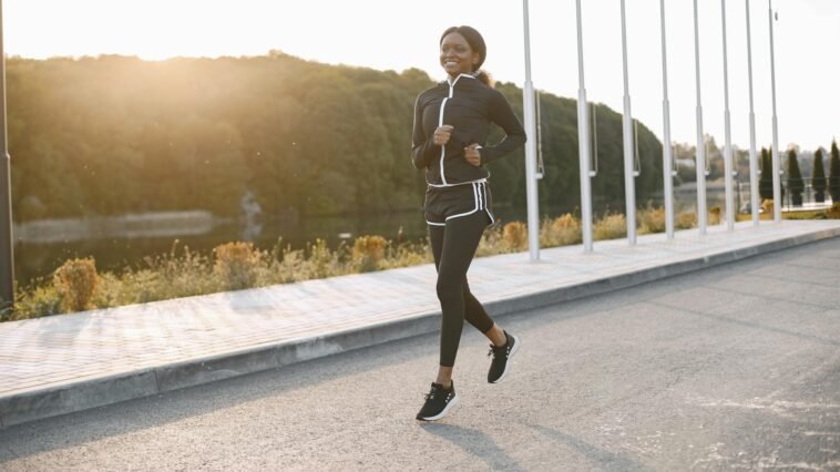 A woman jogging on a sunny outdoor path, showcasing fitness and sport.