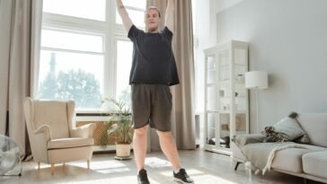 A young man enjoying a morning stretch in a bright, airy living room, embracing a healthy lifestyle.