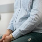 Pregnant woman in casual attire during a healthcare consultation sitting indoors.