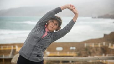 Senior woman stretching outdoors by the seaside in Portugal, embracing a healthy lifestyle.