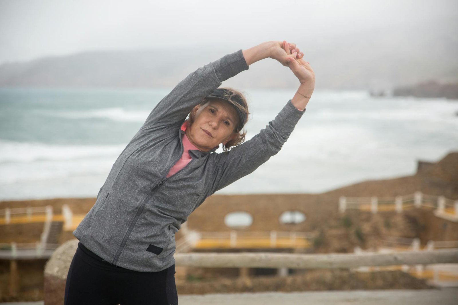 Senior woman stretching outdoors by the seaside in Portugal, embracing a healthy lifestyle.