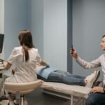 A doctor performs an ultrasound on a pregnant woman, while a man takes a photo in a clinical environment.