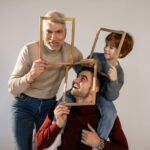 Playful family portrait session with grandfather, father, and son using picture frames.