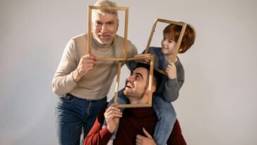 Playful family portrait session with grandfather, father, and son using picture frames.