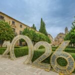 Scenic view of Úbeda, Spain featuring historic architecture and a large 2026 installation amidst orange trees and manicured hedges.