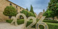 Scenic view of Úbeda, Spain featuring historic architecture and a large 2026 installation amidst orange trees and manicured hedges.