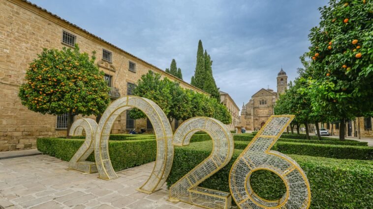 Scenic view of Úbeda, Spain featuring historic architecture and a large 2026 installation amidst orange trees and manicured hedges.