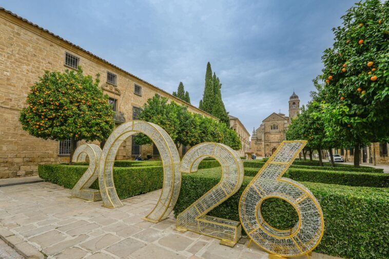 Scenic view of Úbeda, Spain featuring historic architecture and a large 2026 installation amidst orange trees and manicured hedges.
