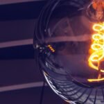 Artistic close-up of an illuminated light bulb with glowing filament and reflections.