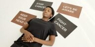 A person lying amidst motivational placards about cancer awareness and resilience.