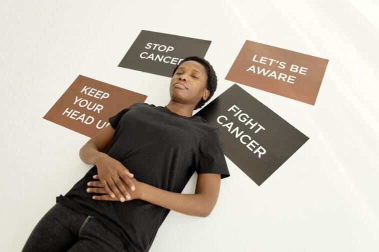 A person lying amidst motivational placards about cancer awareness and resilience.
