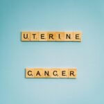 Scrabble tiles spelling 'Uterine Cancer' on a soft blue background, promoting awareness.
