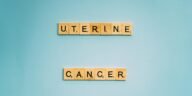 Scrabble tiles spelling 'Uterine Cancer' on a soft blue background, promoting awareness.