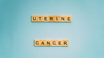 Scrabble tiles spelling 'Uterine Cancer' on a soft blue background, promoting awareness.