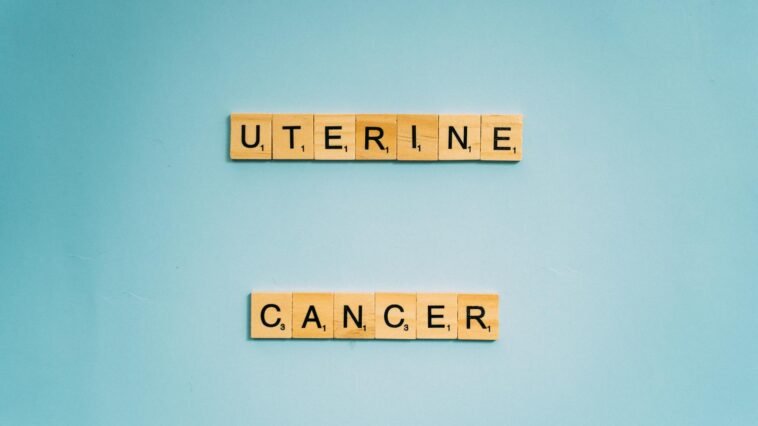 Scrabble tiles spelling 'Uterine Cancer' on a soft blue background, promoting awareness.
