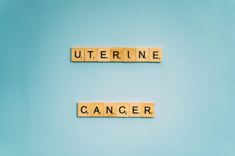 Scrabble tiles spelling 'Uterine Cancer' on a soft blue background, promoting awareness.