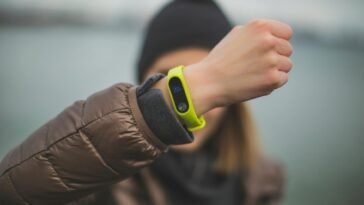 Close-up of a person holding up a fitness tracker, emphasizing technology and active lifestyle.