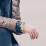 A person wearing a green fitness tracker and winter clothing outdoors. Perfect for health and lifestyle themes.