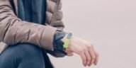 A person wearing a green fitness tracker and winter clothing outdoors. Perfect for health and lifestyle themes.