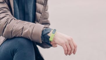 A person wearing a green fitness tracker and winter clothing outdoors. Perfect for health and lifestyle themes.