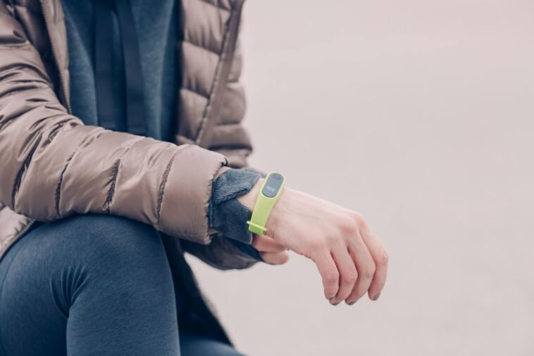 A person wearing a green fitness tracker and winter clothing outdoors. Perfect for health and lifestyle themes.