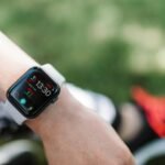 Close-up of a smartwatch on a wrist showing health metrics outdoors on a sunny day.