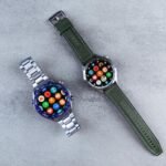 Two smart watches with colorful interfaces displayed on a sleek gray textured surface.