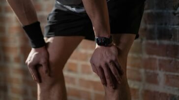 A close-up of an athlete resting after exercise, wearing a digital fitness watch.