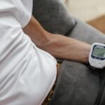 Adult man using a wrist blood pressure monitor to measure blood pressure at home.