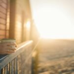 A serene morning scene with a hand holding a mug at sunrise, capturing warmth and tranquility.