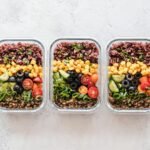 Colorful healthy meal prep with corn, olives, tomatoes, and lentils in glass containers. Perfect for mindful eating.