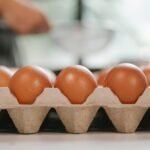 Eggs in carton container placed on table near chef cooking food in kitchen