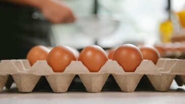 Eggs in carton container placed on table near chef cooking food in kitchen