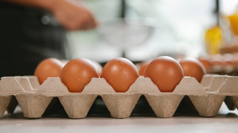Eggs in carton container placed on table near chef cooking food in kitchen