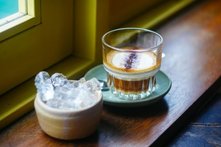 Glass of Vietnamese coffee and ice on a wooden sill in Da Nang's inviting cafe.