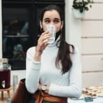 Casual outdoor scene of a woman drinking water at a social gathering, showcasing hydration.