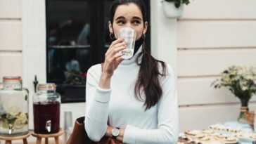 Casual outdoor scene of a woman drinking water at a social gathering, showcasing hydration.