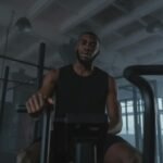 Black man training on exercise bike in modern gym setting, promoting fitness and healthy lifestyle.