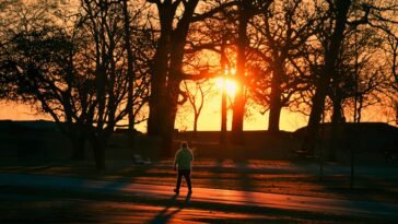 A person walks through Cove Island Park during a vivid autumn sunrise in Stamford, Connecticut.