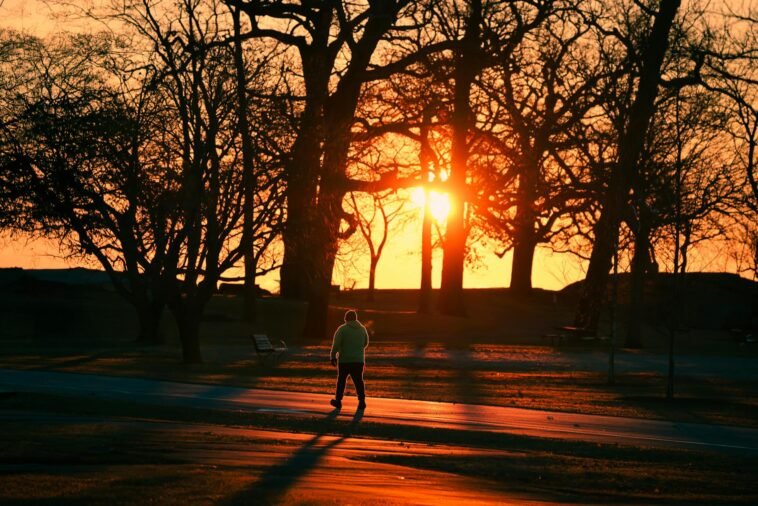 A person walks through Cove Island Park during a vivid autumn sunrise in Stamford, Connecticut.