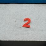 A simple red number 2 on a textured concrete wall with minimalistic design elements.