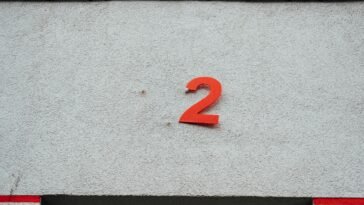 A simple red number 2 on a textured concrete wall with minimalistic design elements.
